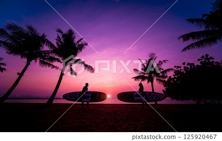 Silhouette of surfers couple holding long surf boards at sunset 125920467