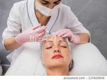 The doctor cosmetologist makes the facial injections procedure. The doctor cosmetologist makes the facial injections procedure. 125920648