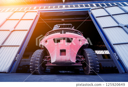 The big industrial forklift drives into the warehouse. The big industrial forklift drives into the warehouse. 125920649