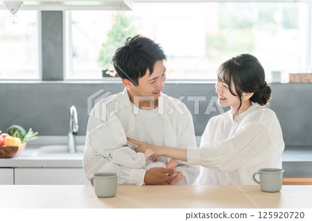 A young couple cradling their baby in the living room and dining room 125920720
