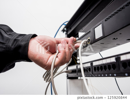 Technician connecting network cables to switches. Connecting cables  125920844