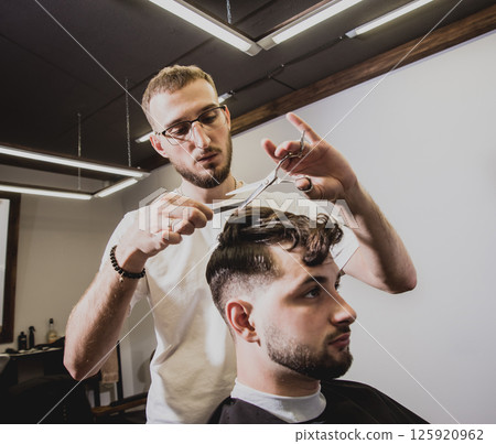 Young man with trendy haircut at barber shop. Young man with trendy haircut at barber shop. 125920962