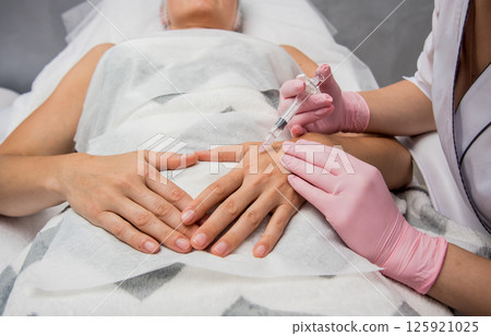 The doctor cosmetologist makes the arms injections procedure. The doctor cosmetologist makes the arms injections procedure. 125921025