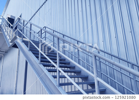 A set of stairs ascending a large blue wall A set of stairs ascending a large blue wall 125921080