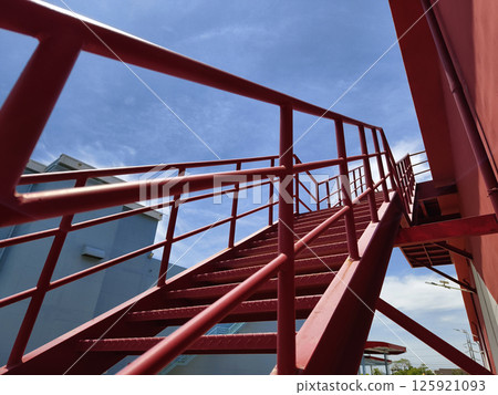 A set of stairs ascending a large red wall 125921093