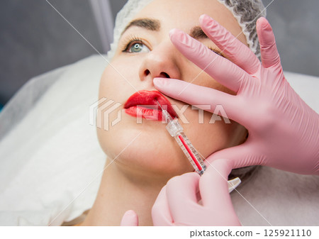 The doctor cosmetologist makes the facial injections procedure.  125921110