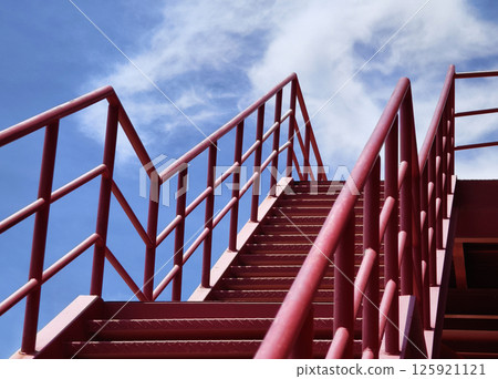 A set of stairs ascending a large red wall A set of stairs ascending a large red wall 125921121