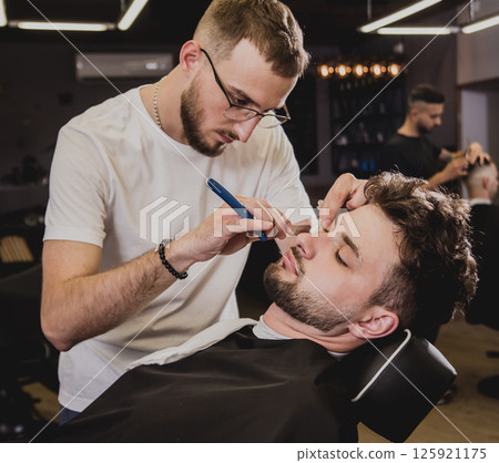 Young man with trendy haircut at barber shop. Young man with trendy haircut at barber shop. 125921175
