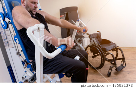 Disabled man doing strength exercises separate from the wheelchair. Disabled man doing strength exercises separate from the wheelchair. 125921378