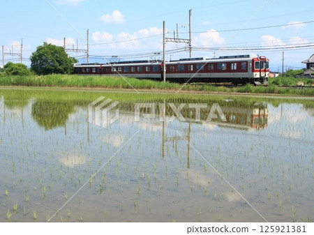 A Kintetsu Line train runs through the rice fields of the Nara Basin as they turn into a mirror-like surface during the rice planting season. A Kintetsu Line train runs through the rice fields of the Nara Basin as they turn into a mirror-like surface during the rice planting season. 125921381