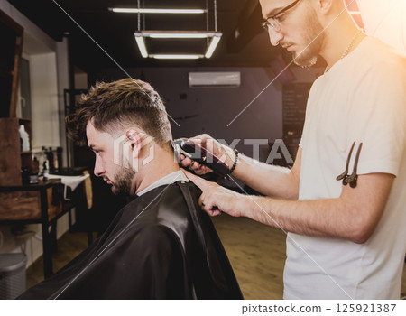 Young man with trendy haircut at barber shop. Young man with trendy haircut at barber shop. 125921387