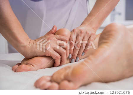 Beautiful young woman enjoying foot massage in spa salon. Cosmetology 125921676