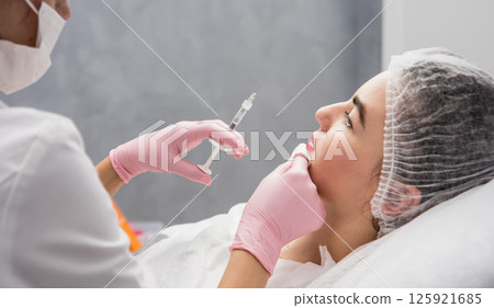 The doctor cosmetologist makes the facial injections procedure.  125921685