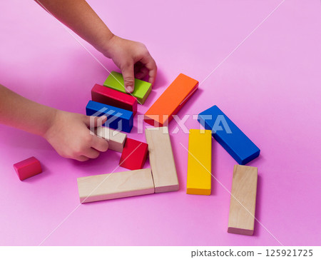 A child with an autism spectrum disorder builds a house from a wooden constructor. Concept of autism. 125921725