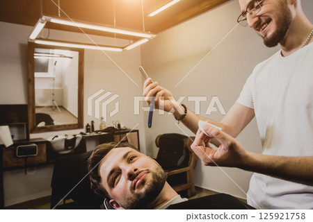 Young man with trendy haircut at barber shop.  125921758