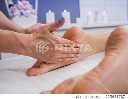 Beautiful young woman enjoying foot massage in spa salon. Cosmetology Beautiful young woman enjoying foot massage in spa salon. Cosmetology 125921787