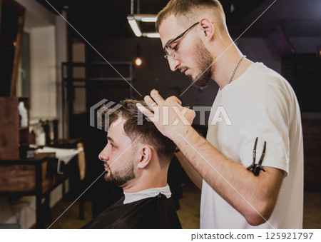 Young man with trendy haircut at barber shop.  125921797