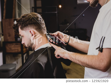 Young man with trendy haircut at barber shop.  125921920