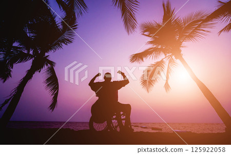 Disabled man in a wheelchair on the beach. Silhouette at sunset. 125922058