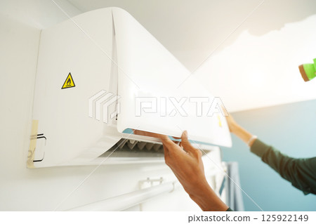 The worker cleans and repairs the air conditioner to ensure it operates properly The worker cleans and repairs the air conditioner to ensure it operates properly 125922149