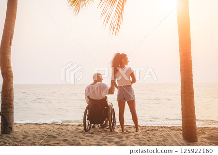 Disabled man in a wheelchair with his wife on the beach. 125922160