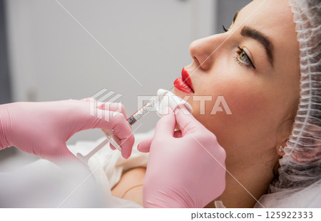 The doctor cosmetologist makes the facial injections procedure.  The doctor cosmetologist makes the facial injections procedure.  125922333