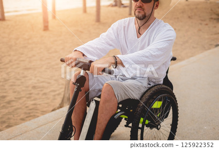 Disabled man in a wheelchair with electric scooter on the beach 125922352