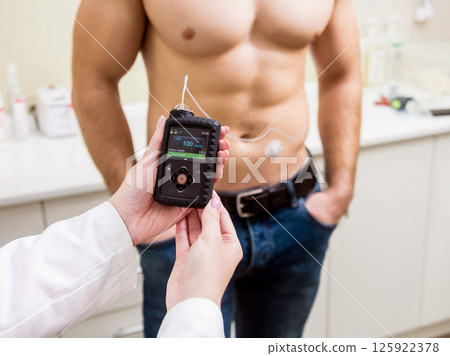 The doctor connects an insulin pump to a patient with diabetes. 125922378