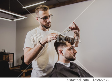 Young man with trendy haircut at barber shop. Young man with trendy haircut at barber shop. 125922379