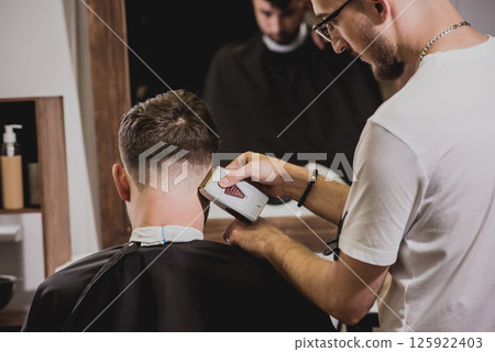 Young man with trendy haircut at barber shop. Young man with trendy haircut at barber shop. 125922403