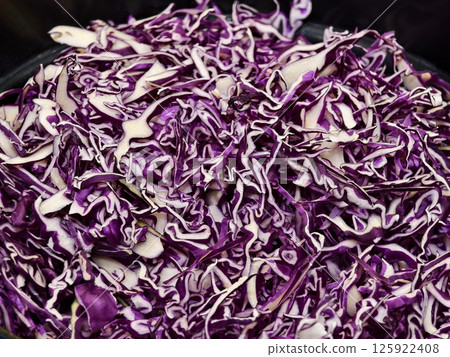 A large pile of finely shredded purple cabbage sits in a black bowl 125922408