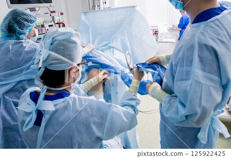 Arthroscope surgery. Orthopedic surgeons in teamwork in the operating room Arthroscope surgery. Orthopedic surgeons in teamwork in the operating room 125922425