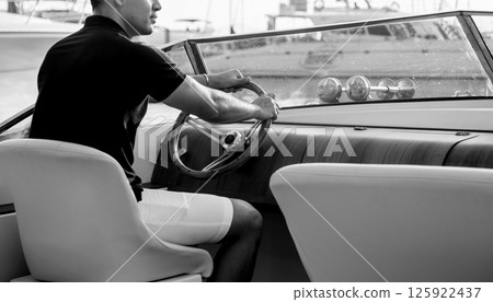 Young man on sailing yacht. Hands hold steering wheel Young man on sailing yacht. Hands hold steering wheel 125922437