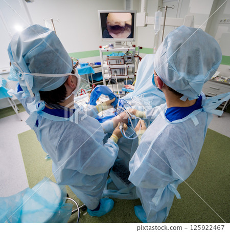 Arthroscope surgery. Orthopedic surgeons in teamwork in the operating room Arthroscope surgery. Orthopedic surgeons in teamwork in the operating room 125922467