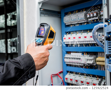 Technician use infrared thermal imaging camera to check temperature at fuse-box Technician use infrared thermal imaging camera to check temperature at fuse-box 125922524