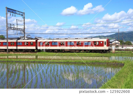 A Kintetsu Line train runs through the rice fields of the Nara Basin as they turn into a mirror-like surface during the rice planting season. A Kintetsu Line train runs through the rice fields of the Nara Basin as they turn into a mirror-like surface during the rice planting season. 125922608