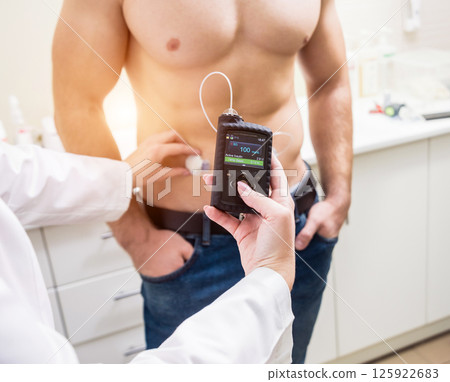 The doctor connects an insulin pump to a patient with diabetes. A concept of diabetes. The doctor connects an insulin pump to a patient with diabetes. A concept of diabetes. 125922683