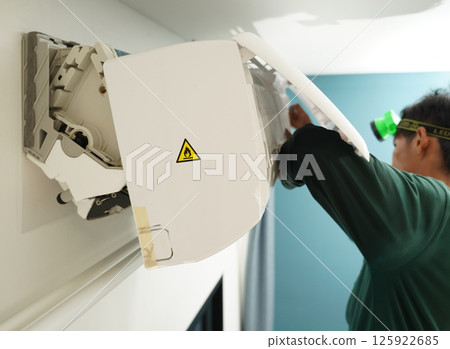 The worker cleans and repairs the air conditioner to ensure it operates properly 125922685