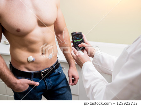 The doctor connects an insulin pump to a patient with diabetes. 125922712