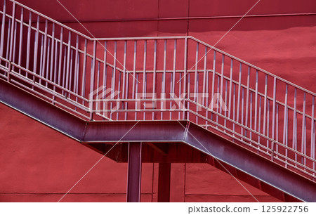 A set of stairs ascending a large red wall 125922756