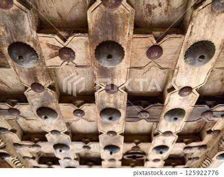 Detailed closeup of an antique wooden door decorated with elegant metal rings mounted on it. 125922776