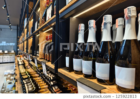 A variety of bottles of champagne are elegantly lined up on a wooden shelf 125922813