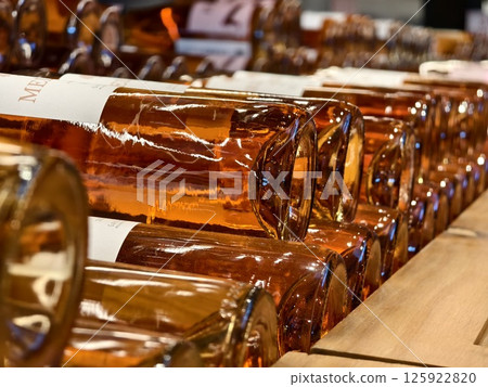 Many bottles of wine neatly arranged on a shop shelf 125922820