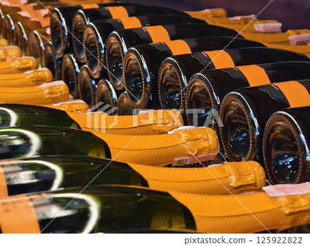 A variety of bottles of champagne are elegantly lined up on a wooden shelf 125922822