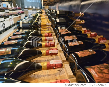 A variety of bottles of champagne are elegantly lined up on a wooden shelf A variety of bottles of champagne are elegantly lined up on a wooden shelf 125922823