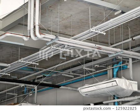 The ceiling of a large building under construction an extensive network of pipes 125922825