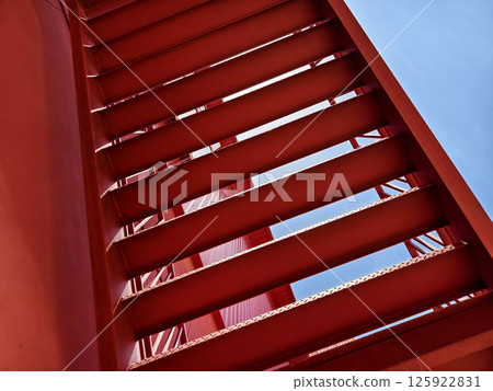 A set of stairs ascending a large red wall 125922831