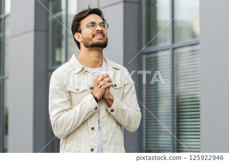 Portrait of Indian man praying with closed eyes to God asking for blessing help forgiveness outdoors 125922946