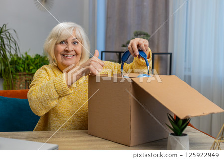 Happy senior woman shopper unpack headphones cardboard box delivery parcel online shopping purchase Happy senior woman shopper unpack headphones cardboard box delivery parcel online shopping purchase 125922949
