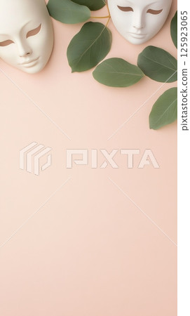 Two white theatrical masks rest on a pink background adorned with eucalyptus leaves. Concept for World Theatre Day with copy space for text 125923065